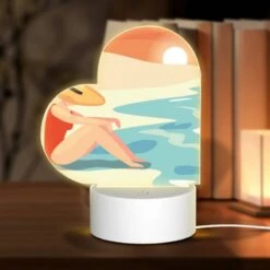 Love Acrylic Night Light, A Woman Wearing A Hat Sits On The Beach.