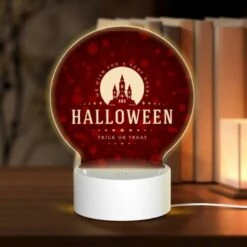 Round Acrylic Night Light, A Halloween Poster With A Castle And A Trick Or Treat Message.